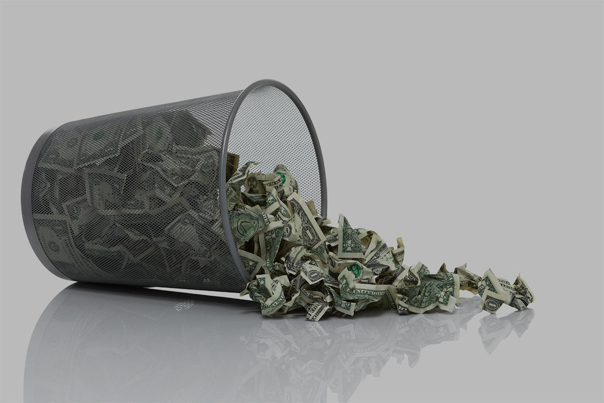 Garbage can full of money tipped on its side with money spilling out